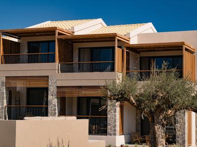 Modernes zweistöckiges Haus mit Holzverkleidung, großen Fenstern und einem Olivenbaum im Vordergrund.