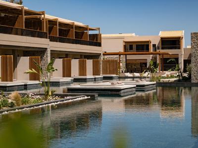 Modernes Hotel mit Terrassen und Wasserbecken in sonniger Umgebung.