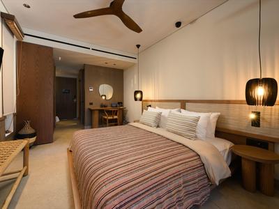 Modernes Schlafzimmer mit großem Bett, hölzernen Möbeln, Deckenventilator und warmem Lichtdesign.