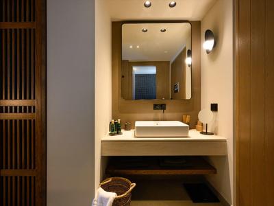 Modernes Badezimmer mit weißem Waschtisch, großem Spiegel und Holzakzenten. Warmes Licht schafft Atmosphäre.