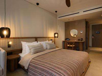 Modernes Hotelzimmer mit Doppelbett, Nachttischen, stilvollen Lampen und einer Arbeitsfläche mit Spiegel.