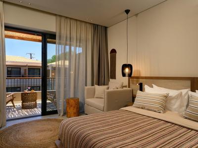 Modern eingerichtetes Schlafzimmer mit großem Bett, Sofa, Holztisch, Teppich und Balkon mit Möbeln.