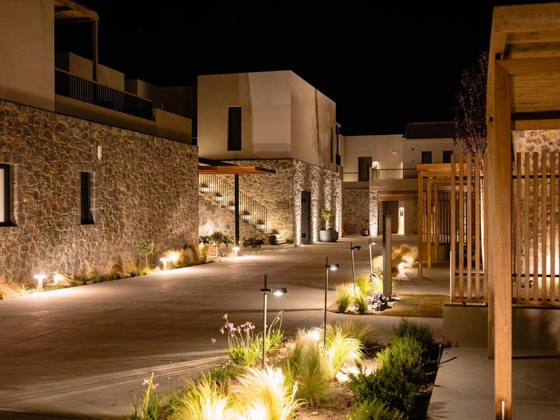 Moderner Innenhof bei Nacht mit warmen Außenleuchten, Pflanzen und klaren Linien.