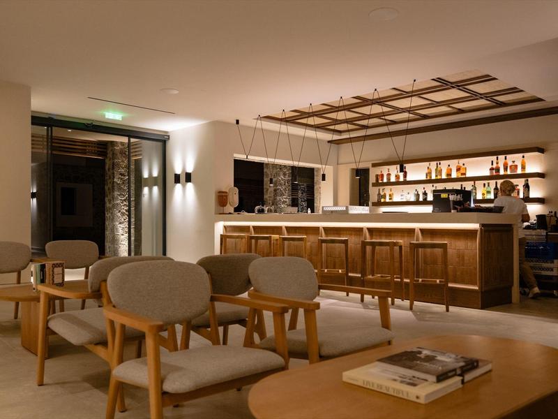 Gemütliche Bar mit Holzstühlen, Theke und warmem Licht in modernem, elegantem Ambiente.