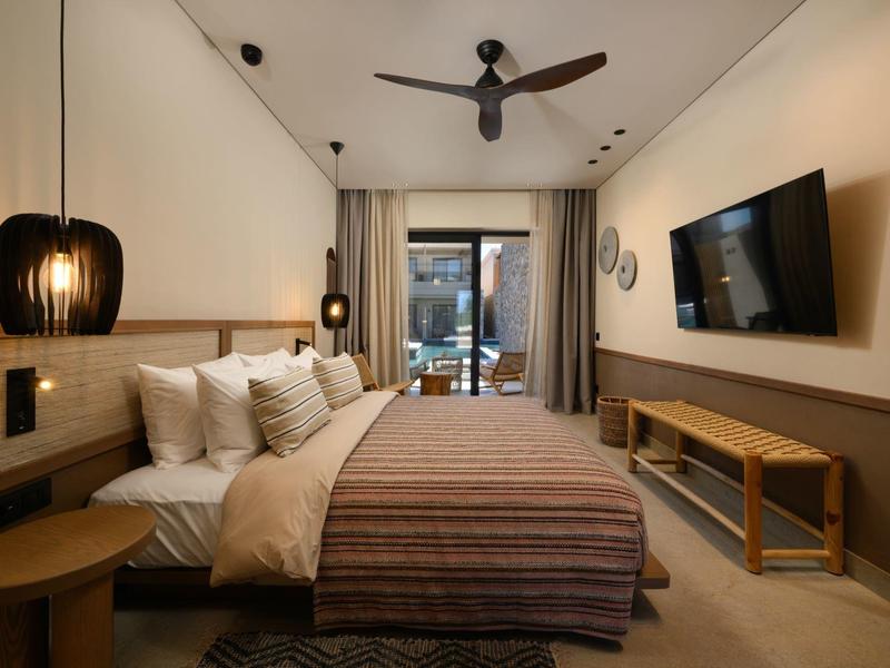 Modernes Schlafzimmer mit großem Bett, deckenhohen Vorhängen, Deckenventilator und Wand-TV.