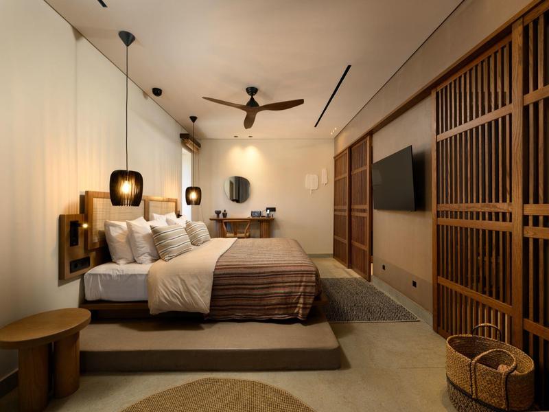 Modernes Schlafzimmer mit großem Bett, Holzpaneelen, Hängeleuchten und Deckenventilator.