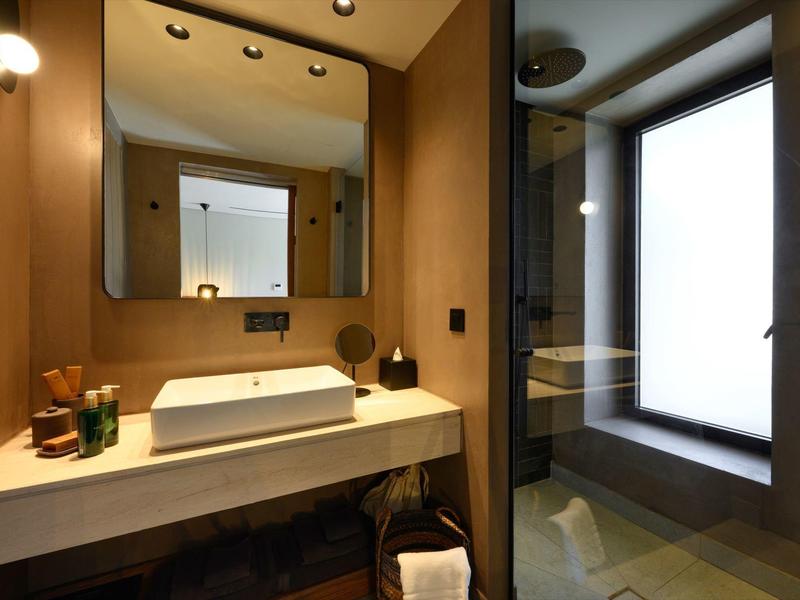 Modernes Badezimmer mit großem Spiegel, weißem Waschbecken und Glasdusche neben Fenster.