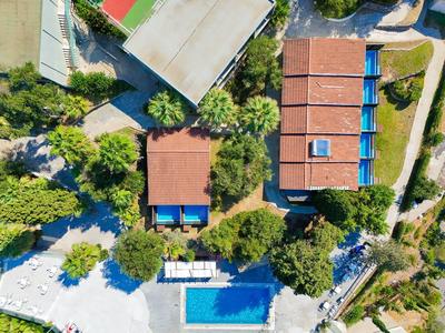 Luchtfoto van een hotel met twee zwembaden, omgeven door bomen en groen.