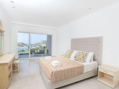 Lichte slaapkamer met tweepersoonsbed, nachtkastjes en uitzicht op terras en bergen.