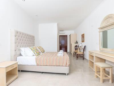 Lichte slaapkamer met tweepersoonsbed, bureau en grote spiegel in hotelkamer.