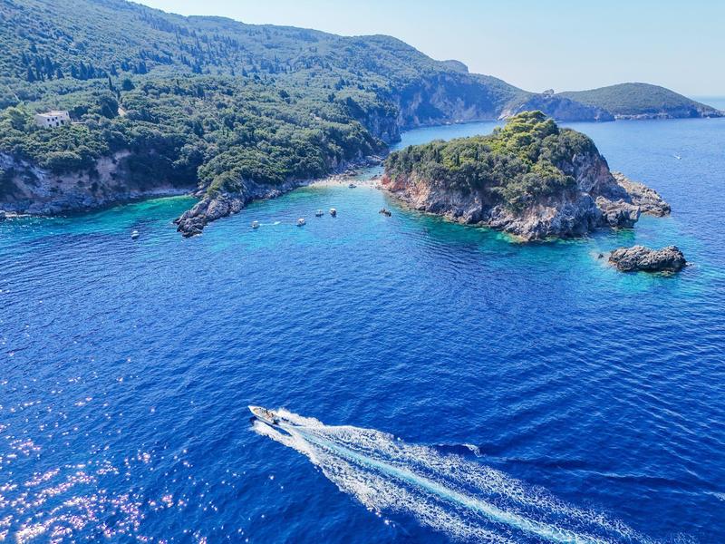 Boot vaart op blauwe zee met beboste eilanden op de achtergrond