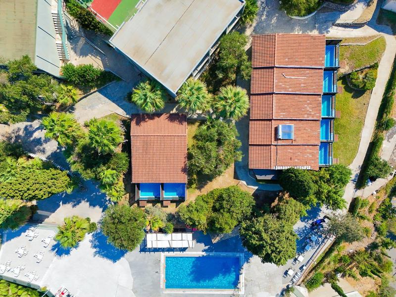 Luchtfoto van een hotel met twee zwembaden, omgeven door bomen en groen.