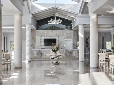 Elegante vestíbulo de hotel con suelo de mármol, columnas blancas y decoración moderna.
