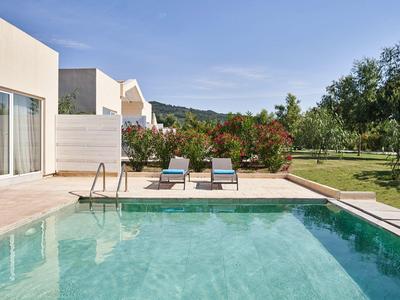 Piscina moderna con lettini e giardino verde in una giornata soleggiata.