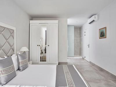 Camera d'hotel luminosa e moderna con letto matrimoniale, armadio e decorazioni neutre.