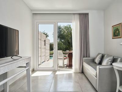 Soggiorno luminoso con divano, TV e vista su una terrazza con giardino.