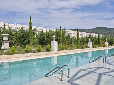 Piscina con scalette, circondata da vegetazione e montagne sullo sfondo.