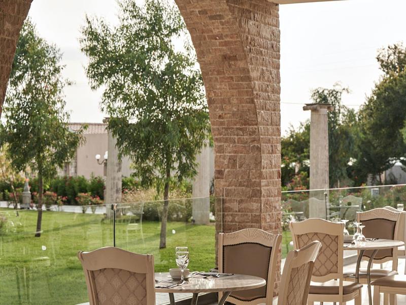 Comode sedute all'aperto sotto un arco di pietra con vista su un paesaggio verde.