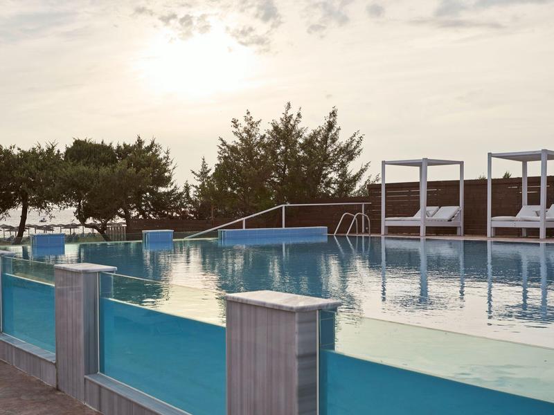 Piscina all'aperto con parapetto in vetro e lettini al tramonto