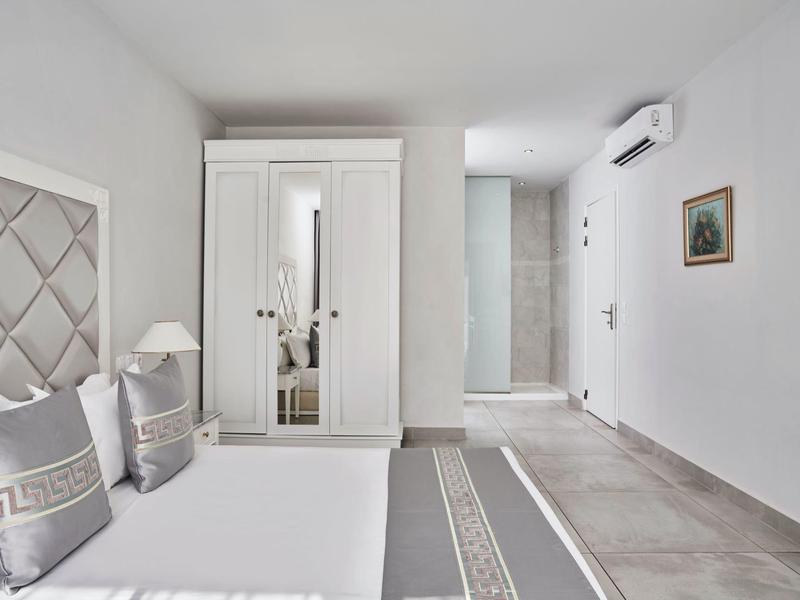 Camera d'hotel luminosa e moderna con letto matrimoniale, armadio e decorazioni neutre.