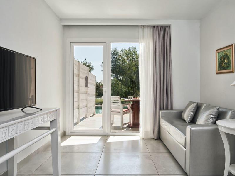 Soggiorno luminoso con divano, TV e vista su una terrazza con giardino.