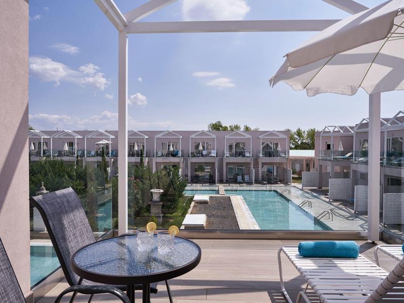 Vista su una piscina con lettini e tavoli sul balcone di un hotel.