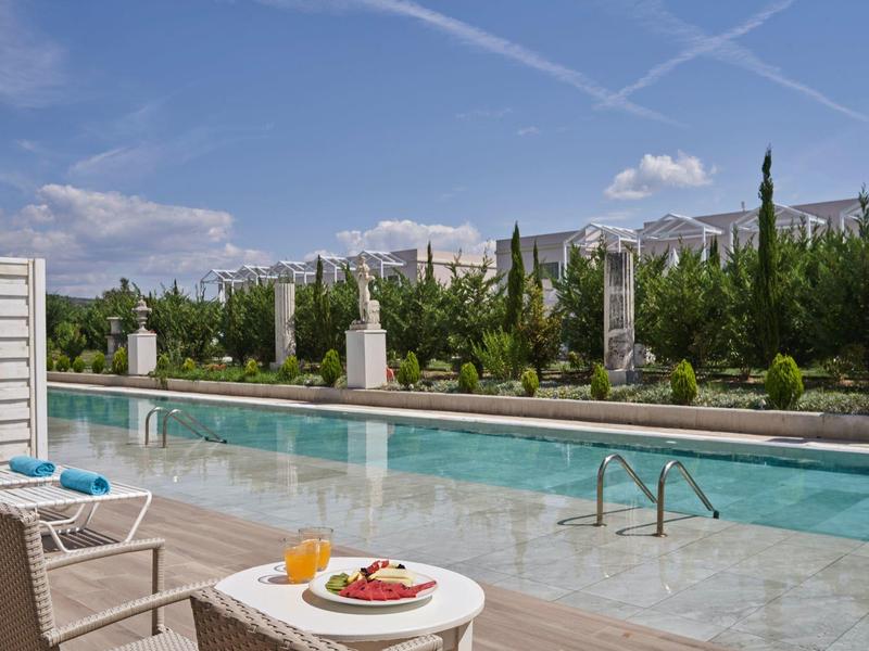 Area piscina moderna con lettini e vista sugli edifici sullo sfondo.