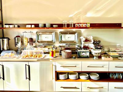 Buffettheke mit verschiedenen Frühstücksgerichten und Geschirr in einem Hotel.