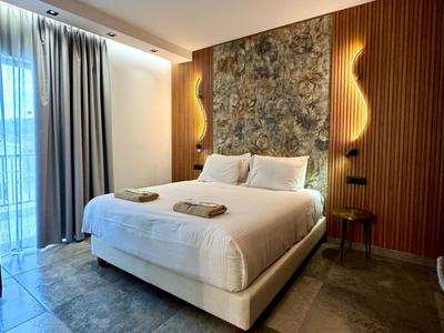 Modernes Hotelzimmer mit großem Bett, Musterwand und Fenster mit Vorhängen.
