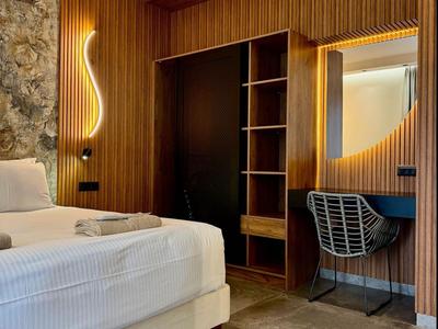 Modernes Hotelzimmer mit Holzwänden, Betten und einem Arbeitsplatz mit rundem Spiegel.