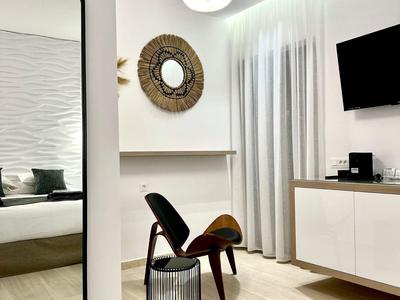 Modernes Hotelzimmer mit Stuhl, rundem Korb, Spiegel und Fernseher an der Wand.