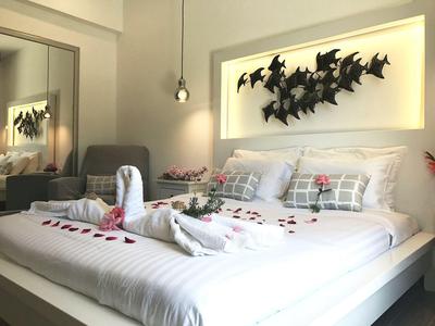 Modernes Hotelzimmer mit weißem Bett, verzierten Handtüchern und Wanddekoration in Fledermausform.