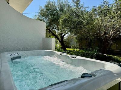 Jacuzzi auf einer Terrasse mit Bäumen im Hintergrund bei klarem Wetter.