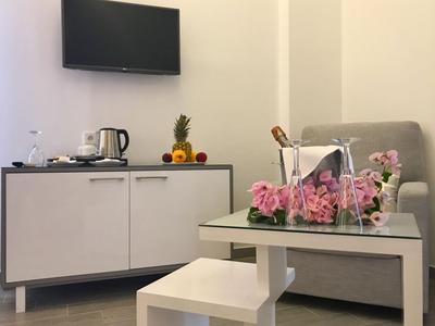 Moderner Hotelzimmerbereich mit Sitzmöbeln, TV, Obst und Blumen als Dekoration.