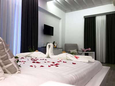 Modernes Hotelzimmer mit weißem Bett, Handtüchern in Schwanform und dunklen Vorhängen.