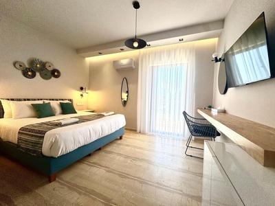 Modernes Hotelzimmer mit Doppelbett, Schreibtisch, TV und großen Fenstern mit Vorhängen.