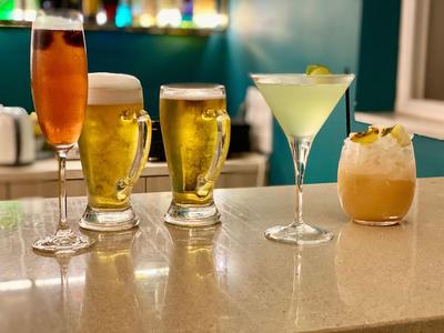 Fünf verschiedenfarbige Getränke auf einer Hotelbar ausgestellt.