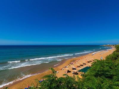 Weicher Sandstrand mit Sonnenschirmen und klarem blauen Himmel am Meer.