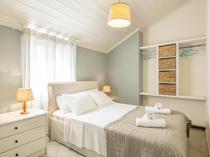 Gemütliches Schlafzimmer mit weißem Doppelbett, grauer Wand und Nachttischen mit Lampen.