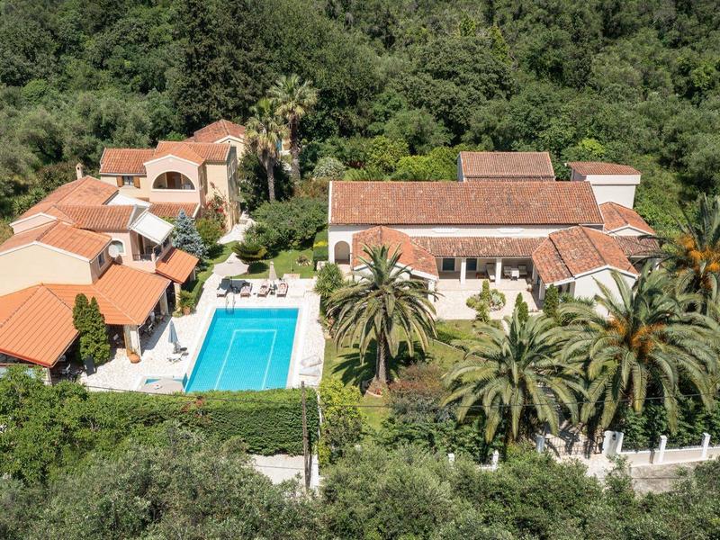 Großes Anwesen mit roten Dächern, Pool und Palmen, umgeben von dichtem grünen Wald.