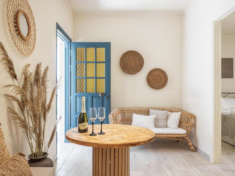 Helles Wohnzimmer mit blauem Türrahmen, runden Körben an der Wand und einem runden Holztisch.