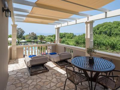 Terrassenbereich mit runder Metalltisch, Stühlen, Sitzsofas und Blick auf grüne Landschaft.