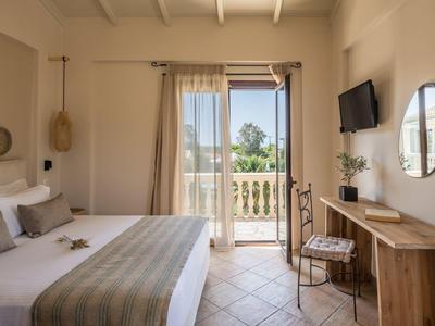 Helles Schlafzimmer mit Doppelbett, Holzmöbeln, Balkon und Fernseher an der Wand.