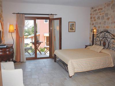 Gemütliches Schlafzimmer mit Doppelbett, Steinwand, Nachttischen und großen Glastüren zum Balkon.