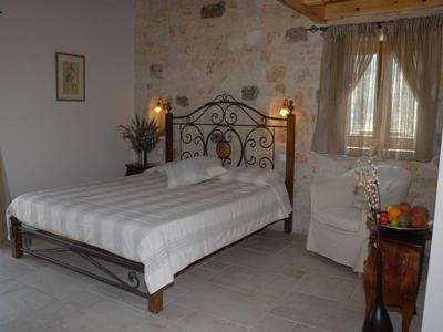 Ein gemütliches Schlafzimmer mit gekacheltem Boden, Doppelbett mit Metallrahmen und Steinwand.