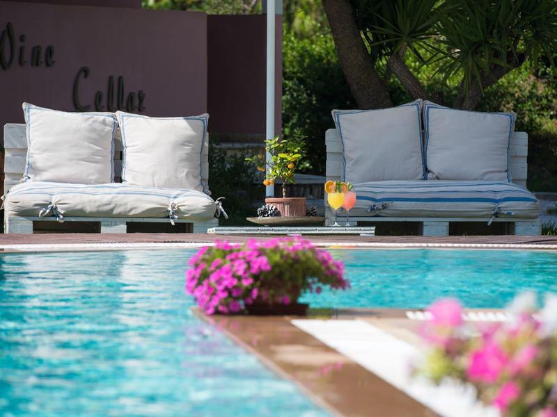 Twee witte banken staan bij het zwembad met bloemen op de voorgrond.