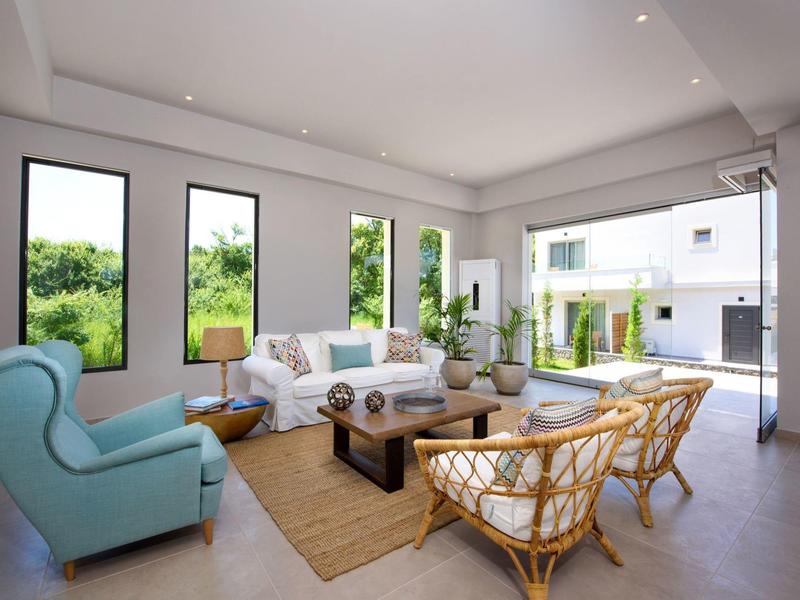 Lichte woonkamer met grote ramen, moderne meubels en toegang tot een terras.