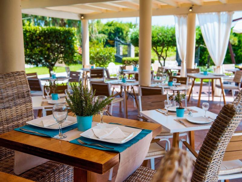 Terrasrestaurant met gedekte tafels met uitzicht op tuin en zwembad