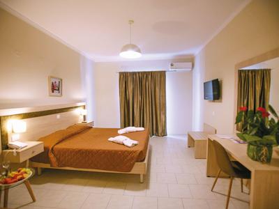 Jasny pokój hotelowy z podwójnym łóżkiem, biurkiem, telewizorem płaskoekranowym i zasłonami na oknach.