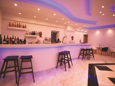 Nowoczesny bar hotelowy z podświetlanym barem i stołkami w jasnym pomieszczeniu.